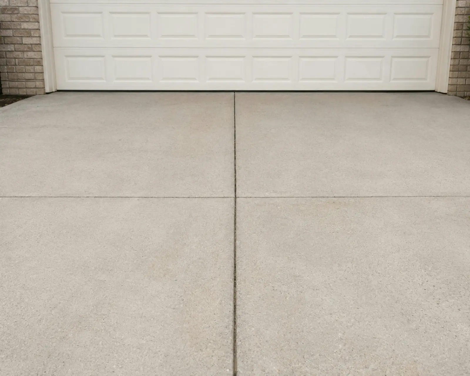 Clean concrete driveway in front of a white garage door