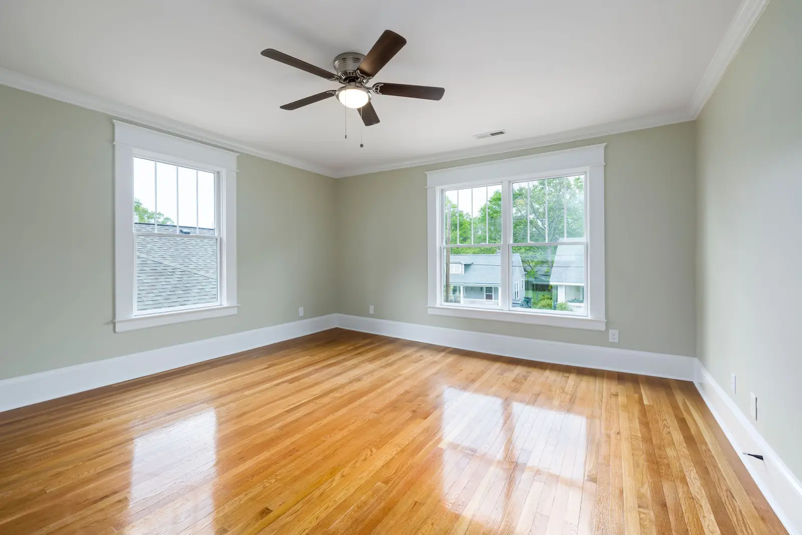 Empty room with polished hardwood floors and two windows