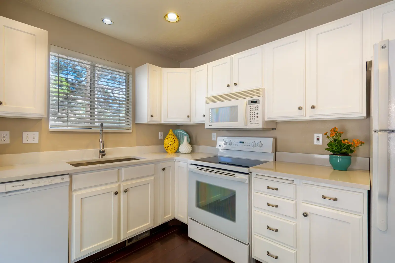 Clean white kitchen with a window, flowers and a bowl of lemons