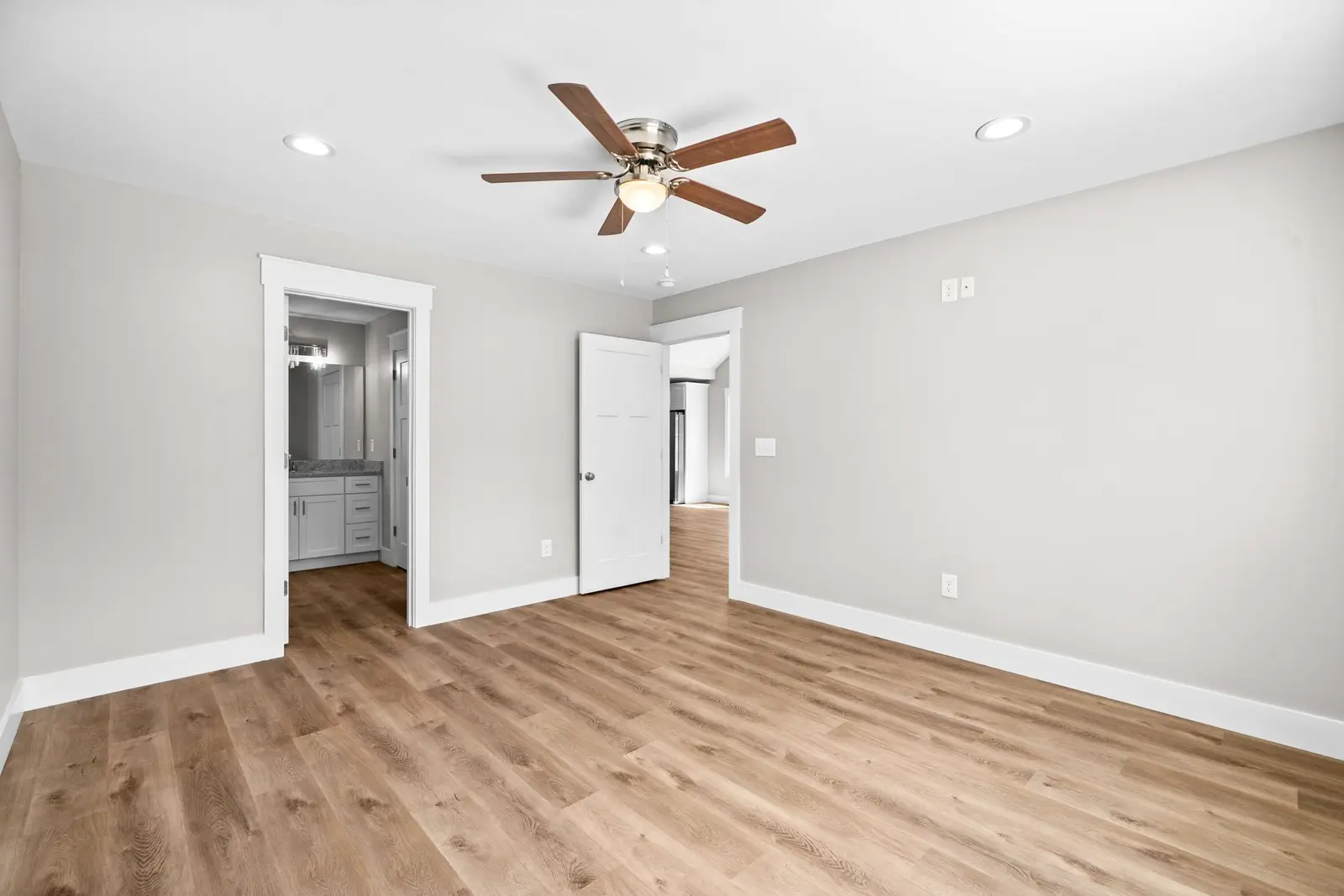 Newly finished empty room with plank flooring and a ceiling fan