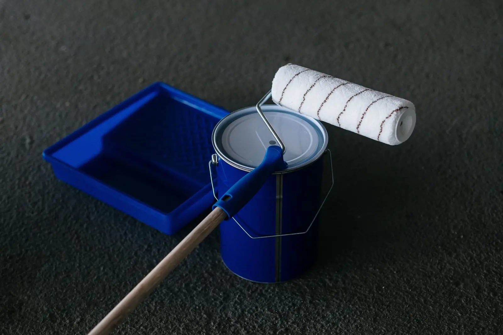 Blue paint roller resting on an open can of paint
