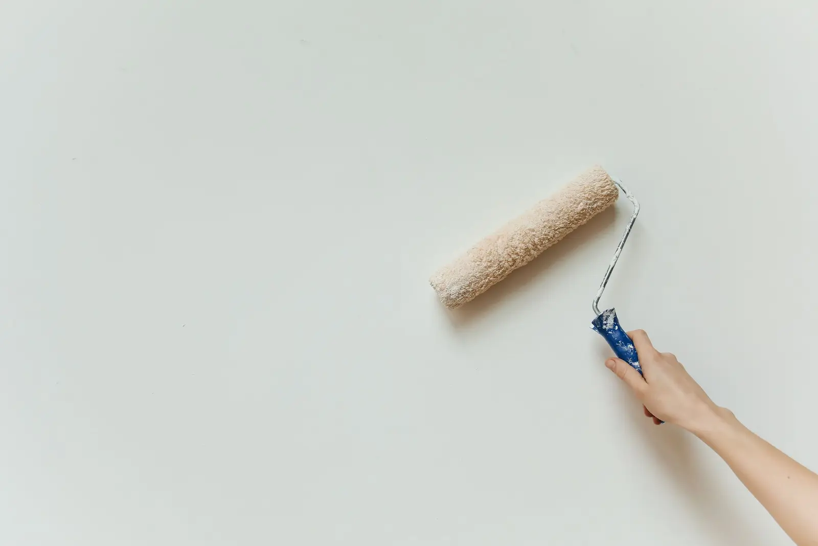 Hand rolling fresh white paint across a smooth interior wall